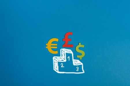 Paper symbols of euro, dollar and british pound currency on podium, blue background. View from above...