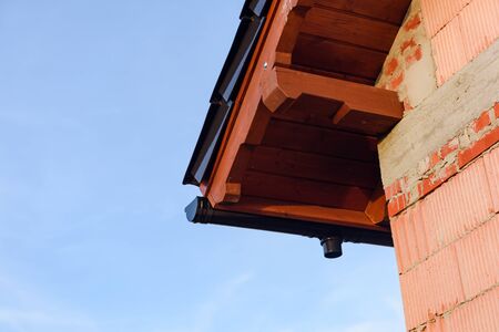 Exterior of a Unfinished Red Brick House Walls under Construction with Roof. opy space. Blue Sky.