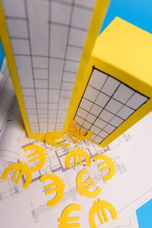Paper skyscrapers , euro money, house projects plan and blueprints on blue background paper. Minimalistic and simple concept, style. Vertical orientation. View from above.の写真素材