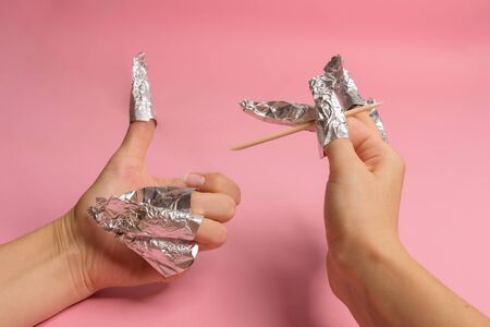 The procedure for removing varnish from nails hybrid nails in progress. Gel nail polish remover foils on woman's handsの写真素材