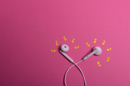 white earphones and yellow paper notes on pink background. view from aboveの写真素材