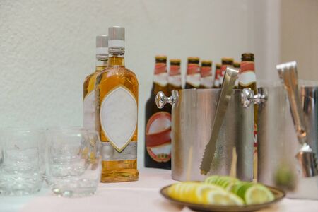 Bottle of cold vodka and wine bottle in bucket with ice and orange juice in jug on table, copy space. Alcohol bottles in ice bucket in restaurant. Wedding partyの写真素材