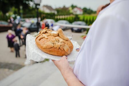 Traditional polish greeting the bride and groom by the parents with bread and salt. Vodka also in glasses.の写真素材