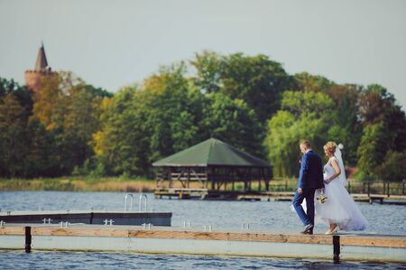 Bride and groom at a photo session in the nature. Lake and pier.の写真素材