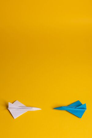 Group of paper plane in one direction and with one individual pointing in the different way on yellow background. Smoke coming out from aircraft tailsの写真素材