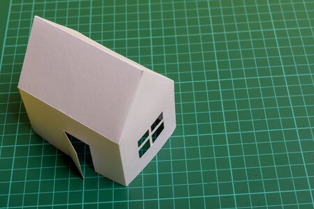 White family paper house over block of flats on yellow background paper. Minimalistic and simple concept, style. Copy space. Vertical orientation.の写真素材