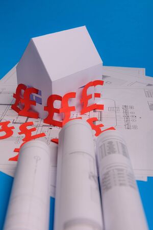 White family paper house , british pound money symbol , house projects plan and blueprints on mint background paper. Minimalistic and simple concept, style. Vertical orientation. View from above. copy spaceの写真素材