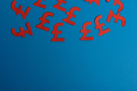Paper yellow symbols of british pound currency on blue background. View from above with copy spaceの写真素材