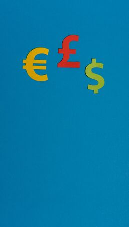 Paper yellow symbols of euro, dollar and pound currency on blue background. View from above with copy spaceの写真素材