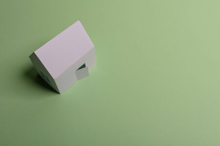 White family paper house , stack of money coins, house projects plan and blueprints on mint background paper. Minimalistic and simple concept, style. Vertical orientationの写真素材