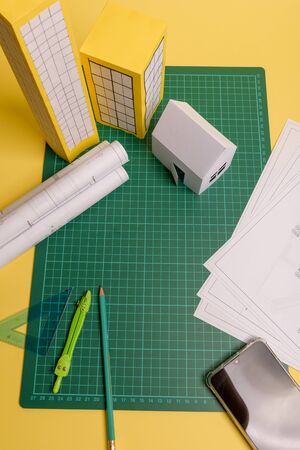 White family paper house over block of flats on yellow background paper. Minimalistic and simple...