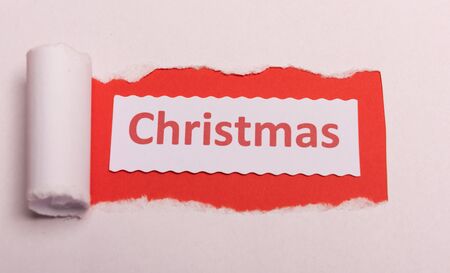 White torn paper with CHristmas text with red background color. Hidden message. Secret. Copy spaceの写真素材