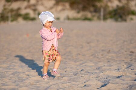 Adorable toddler girl on a sunny sand beach. Authentic lifestyle childhood imageの写真素材