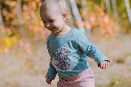 Adorable girl having fun on beautiful autumn day. Authentic picture.の写真素材