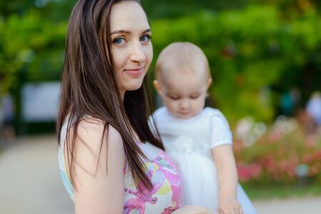 Happy mother and daughter in the park. Beauty nature scene with family outdoor lifestyle. Happy family resting together on the green grass, authentic lifestyle imageの写真素材