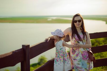 Happy mother and daughter in the park. Beauty nature scene with family outdoor lifestyle. Happy family resting together on the green grass, authentic lifestyle imageの写真素材