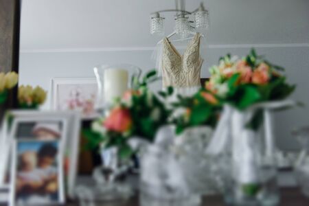 Bridesmaid helping slender bride lacing her wedding white dress, buttoning on delicate lace pattern with fluffy skirt on waist. Morning bridal preparation details newlyweds. Wedding day moments, wear.の写真素材