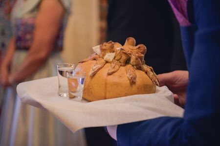 Traditional polish greeting the bride and groom by the parents with bread and salt. Vodka also in glasses.の写真素材