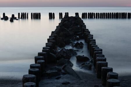 A photograph of wooden breakwater and seagulls at sunset on the Baltic Seaの写真素材