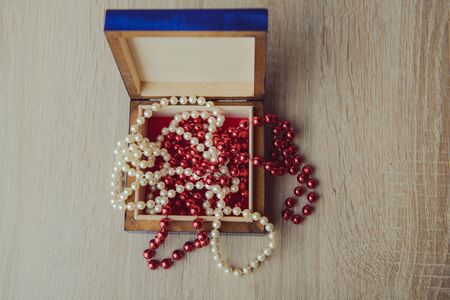 A photograph of gift box and red beads necklace on wooden backgroundの写真素材
