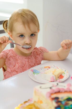 Baby girl 1 year old eating birthday cake in room. Birthday party. Childhood.の写真素材