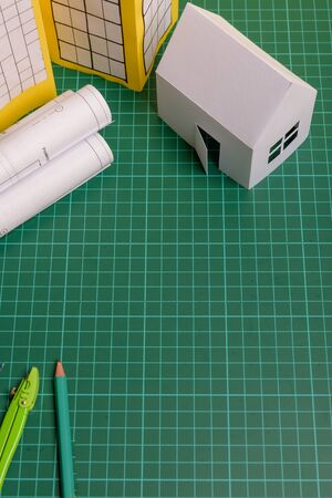 White family paper house, house projects plan and blueprints in the background. Minimalistic and simple concept, style. Horizontal orientation. View from above.の写真素材