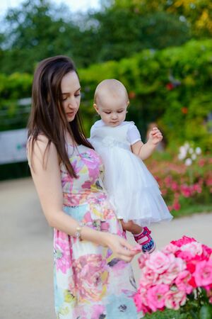 Happy mother and daughter in the park. Beauty nature scene with family outdoor lifestyle. Happy family resting together on the green grass, having fun outdoor. Happiness and harmony in family life.の写真素材