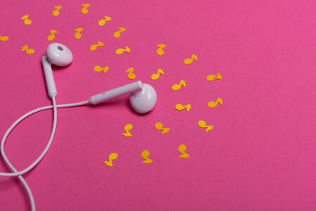 white earphones and yellow paper notes on pink background. view from aboveの写真素材