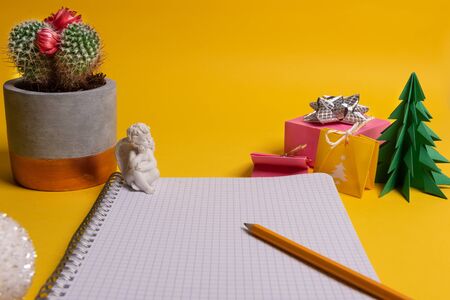 gift box and green origami trees with notepad on yellow desk, tableの写真素材