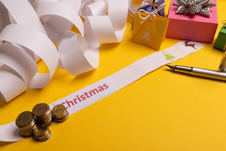 Holiday expenses concept. Long twisted christmas expenses list, presents, gifts, money coins and christmas textの写真素材