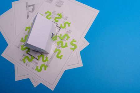 Paper skyscrapers , us dollar money, house projects plan and blueprints on blue background paper. Minimalistic and simple concept, style. Horizontal orientation. View from above. Copy space.の写真素材