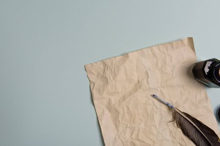 Raven feather, inkwell and old yellowed paper on red background. Copy space. Old letter.の写真素材