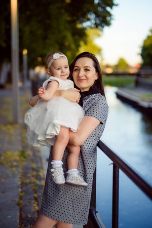 Happy mother and daughter in the park. Beauty nature scene with family outdoor lifestyle. Happy family resting together on the green grass, having fun outdoor. Happiness and harmony in family life.の写真素材