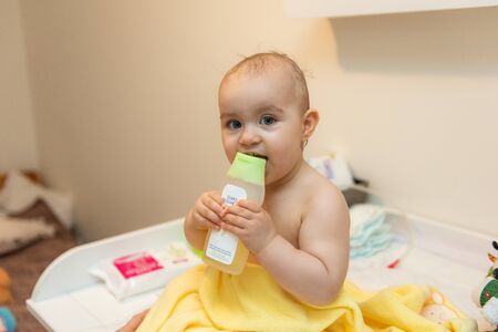 Adorable baby girl sitting under a hooded towel after bath.の写真素材