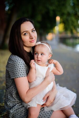 Happy mother and daughter in the park. Beauty nature scene with family outdoor lifestyle. Happy family resting together on the green grass, having fun outdoor. Happiness and harmony in family life.の写真素材