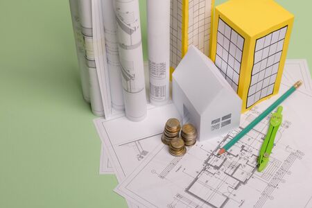 White family paper house, house projects plan and blueprints in the background. Minimalistic and...