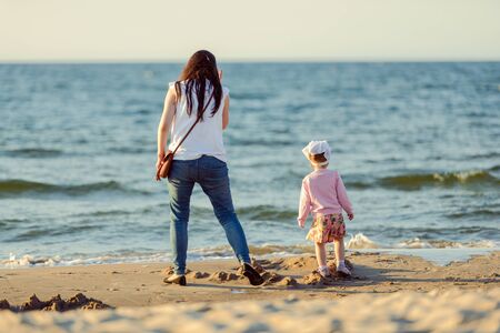 Mother and little daughter walking on the beach.の写真素材