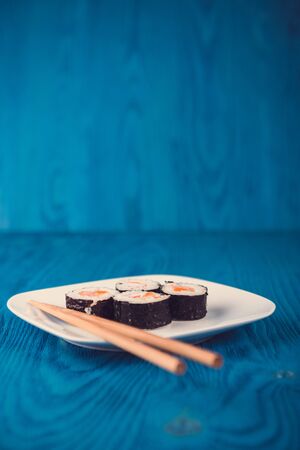 Appetizing tasty Japan rolls on a plate isolated on blue wooden backgroundの写真素材