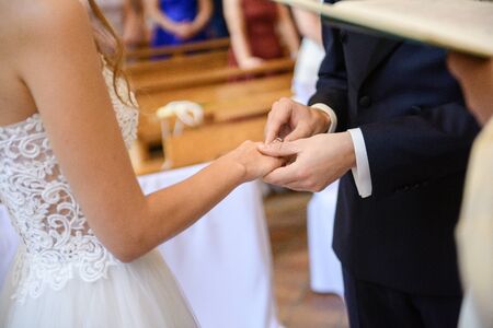 the bride and groom during the wedding ceremony put wedding rings on their fingers.の写真素材
