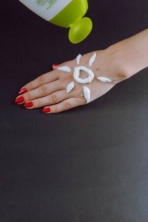 woman applying sunscreen cream on Hand. Red nails.の写真素材