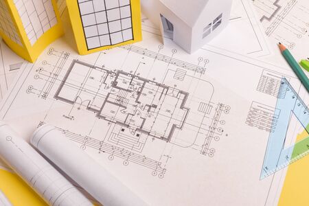 White family paper house, house projects plan and blueprints in the background. Minimalistic and...
