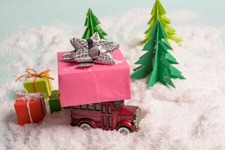 a toy car carries presents under the Christmas tree at snow. view from above. copy spaceの写真素材