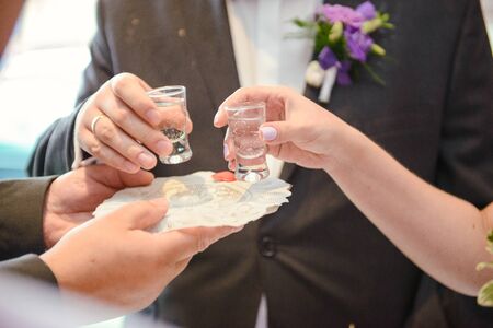 Traditional polish greeting the bride and groom by the parents with bread and salt. Vodka also in glasses.の写真素材