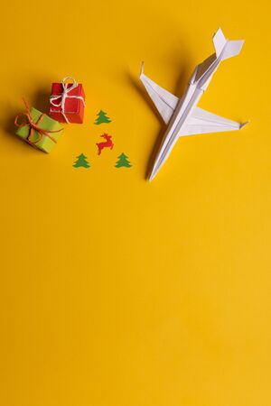 Group of paper plane in one direction and with one individual pointing in the different way on yellow background. Christmas ttrip. Presents and giftsの写真素材
