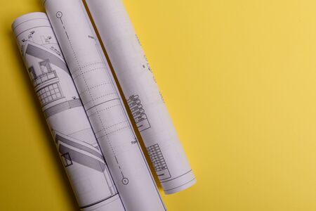 White family paper house, house projects plan and blueprints in the background. Minimalistic and simple concept, style. Horizontal orientation. View from above.の写真素材