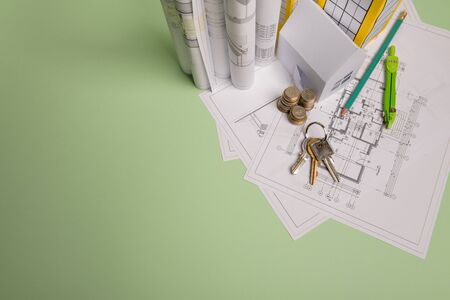 White family paper house. House keys in hand on mint background paper. Minimalistic and simple concept, style. Copy space. Vertical orientation. Family moving or removal concept.の写真素材