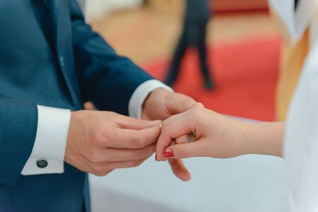 the bride and groom during the wedding ceremony put wedding rings on their fingers.の写真素材