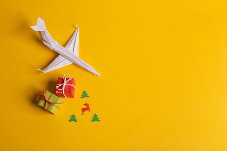 Group of paper plane in one direction and with one individual pointing in the different way on yellow background. Christmas ttrip. Presents and giftsの写真素材