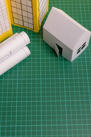 White family paper house, house projects plan and blueprints in the background. Minimalistic and simple concept, style. Horizontal orientation. View from above.の写真素材