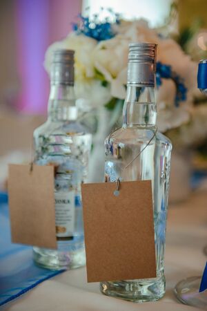 Bottle of cold vodka and wine bottle in bucket with ice and orange juice in jug on table, copy space. Alcohol bottles in ice bucket in restaurant. Wedding partyの写真素材